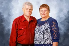 Портрет пожилой пары Под масло: мужчина в красной рубашке и женщина в синем узорчатом платье изображены на нейтральном фоне, художник Мария 