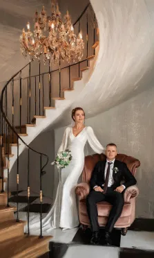 Парный свадебный портрет Под масло, мужчина в классическом костюме с галстуком сидит на кожаном кресле, рядом девушка в белом свадебном платье с букетом, художник Александра 