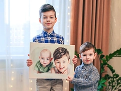 Два маленьких брата держат в руках свой портрет, написанный на холсте по фотографии, на которой они были изображены еще в более раннем возрасте