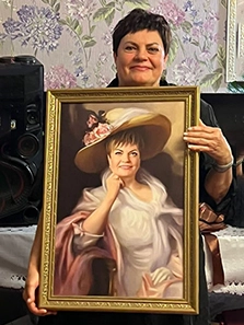 Женщина держит в руках подарок — портрет по ее фотографии на холсте в образе, портрет в раме